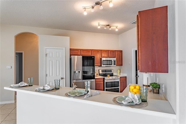 kitchen featuring appliances with stainless steel finishes, kitchen peninsula, a textured ceiling, and light tile patterned floors