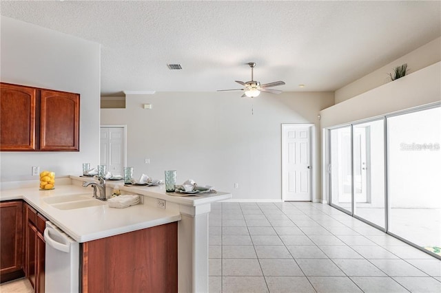 kitchen featuring sink, light tile patterned floors, a textured ceiling, stainless steel dishwasher, and kitchen peninsula