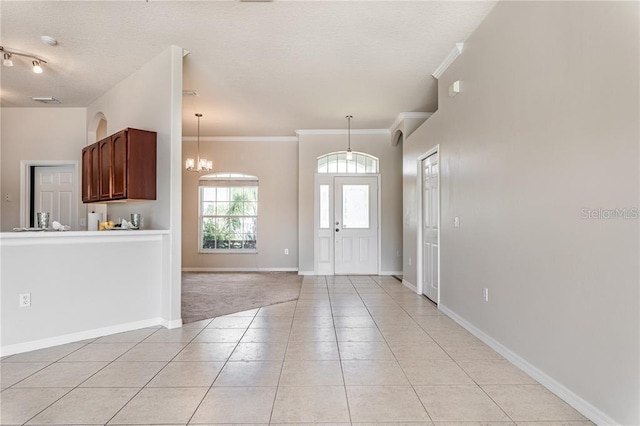 tiled foyer with ornamental molding and a notable chandelier