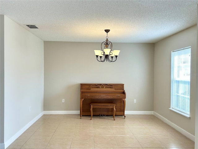 miscellaneous room with light tile patterned floors, a textured ceiling, and an inviting chandelier