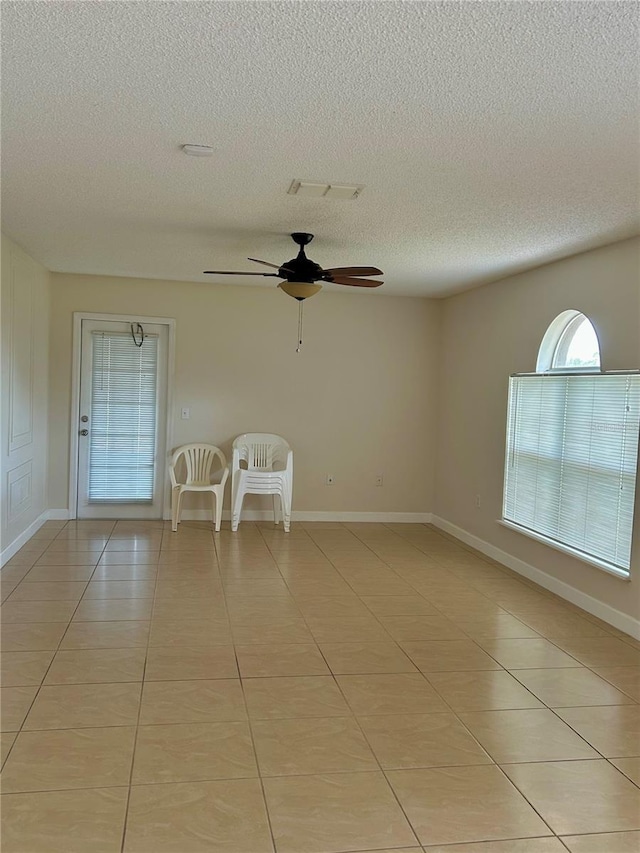 tiled spare room featuring a textured ceiling and ceiling fan