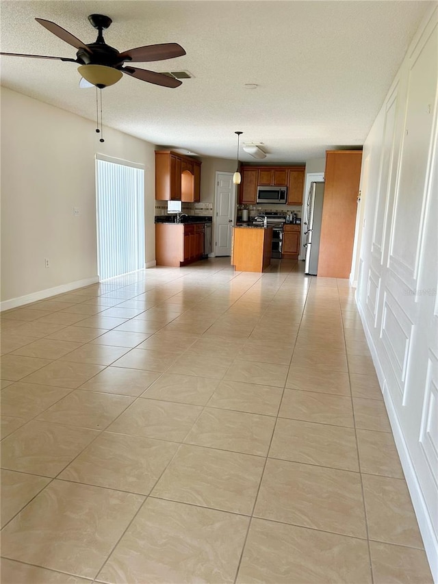 kitchen with light tile patterned flooring, appliances with stainless steel finishes, a kitchen island, pendant lighting, and ceiling fan