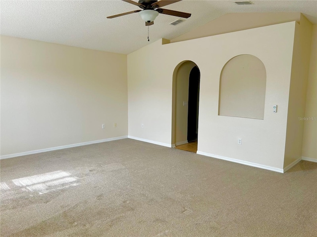 spare room featuring vaulted ceiling, light colored carpet, a textured ceiling, and ceiling fan