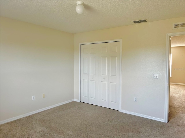 unfurnished bedroom featuring carpet, a textured ceiling, and a closet