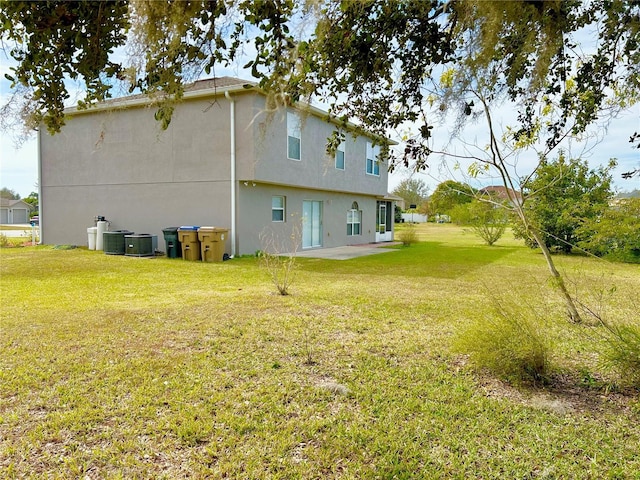 rear view of house with central air condition unit and a lawn