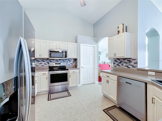 kitchen featuring light tile patterned flooring, high vaulted ceiling, appliances with stainless steel finishes, decorative backsplash, and white cabinets