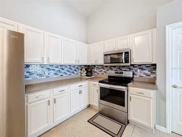 kitchen with light tile patterned floors, stainless steel appliances, white cabinets, light countertops, and tasteful backsplash