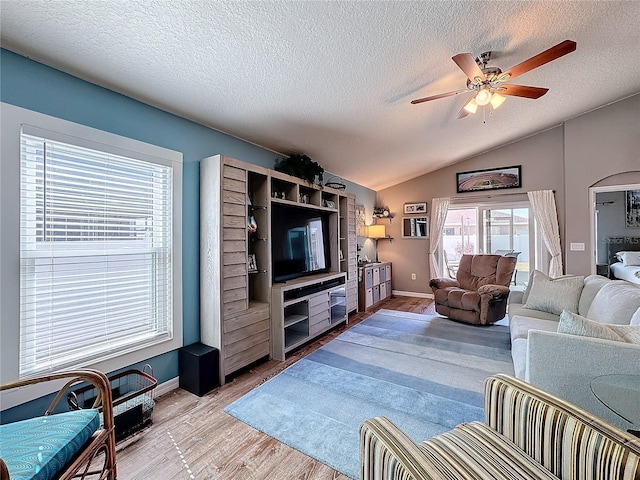 living room with ceiling fan, lofted ceiling, light hardwood / wood-style flooring, and a textured ceiling