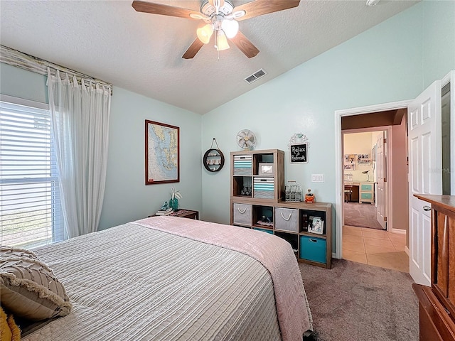 carpeted bedroom featuring ceiling fan, vaulted ceiling, and a textured ceiling