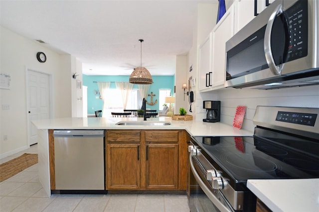 kitchen featuring appliances with stainless steel finishes, decorative light fixtures, sink, backsplash, and kitchen peninsula