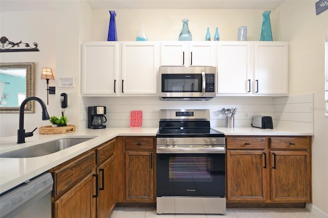 kitchen featuring sink, light tile patterned floors, appliances with stainless steel finishes, white cabinets, and decorative backsplash