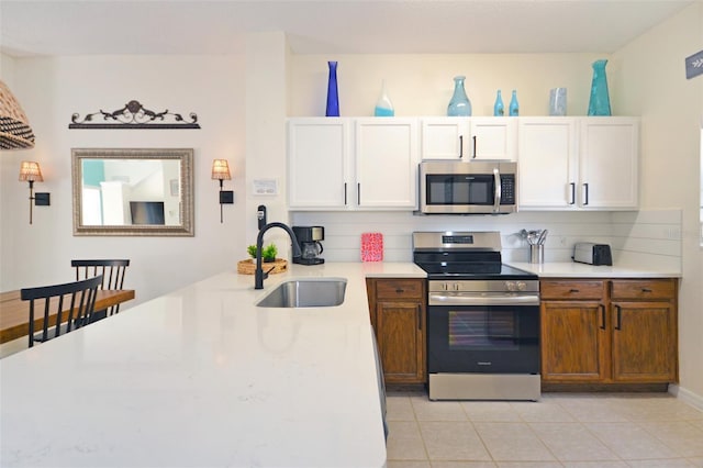 kitchen featuring backsplash, stainless steel appliances, sink, and white cabinets