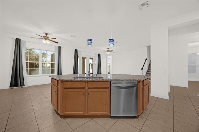 kitchen with light tile patterned flooring, decorative light fixtures, sink, stainless steel dishwasher, and a center island with sink