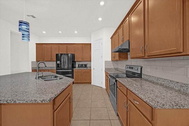 kitchen featuring an island with sink, sink, black fridge, light stone countertops, and stainless steel electric range