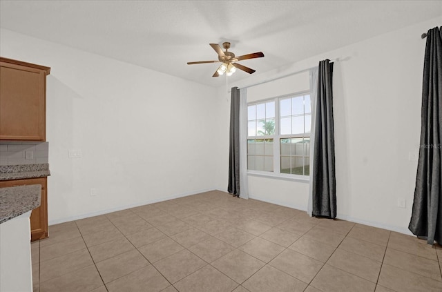 unfurnished room with ceiling fan and light tile patterned flooring