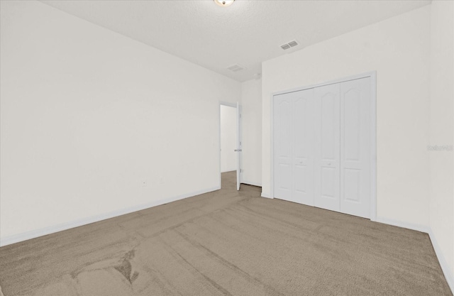 unfurnished bedroom featuring a closet, a textured ceiling, and carpet