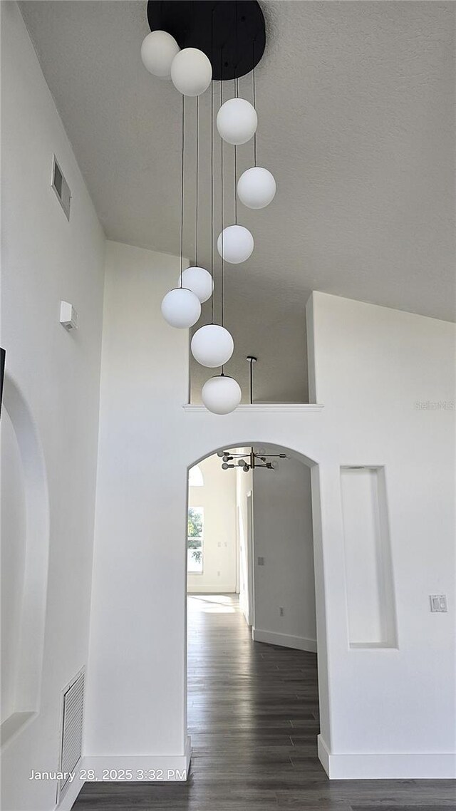 corridor featuring a towering ceiling and dark hardwood / wood-style floors