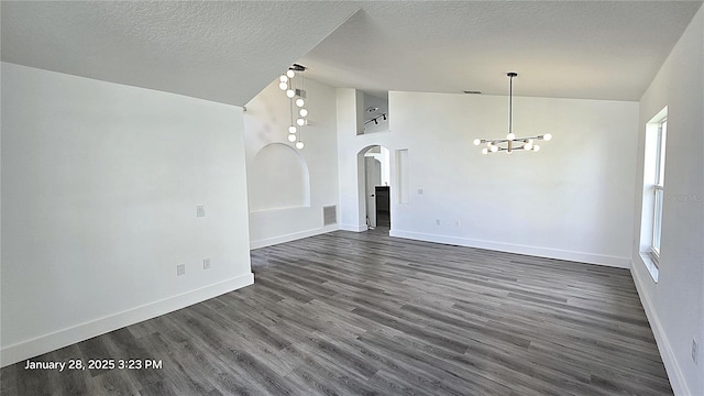 spare room with high vaulted ceiling, dark wood-type flooring, a textured ceiling, and an inviting chandelier