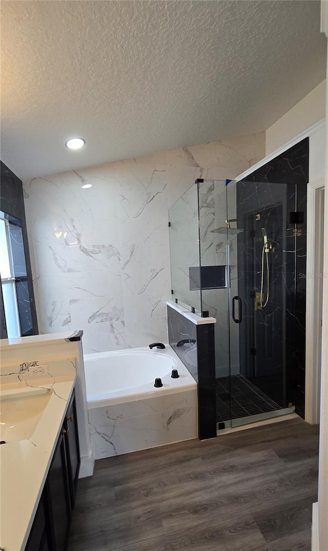 bathroom with wood-type flooring, independent shower and bath, a textured ceiling, and vanity