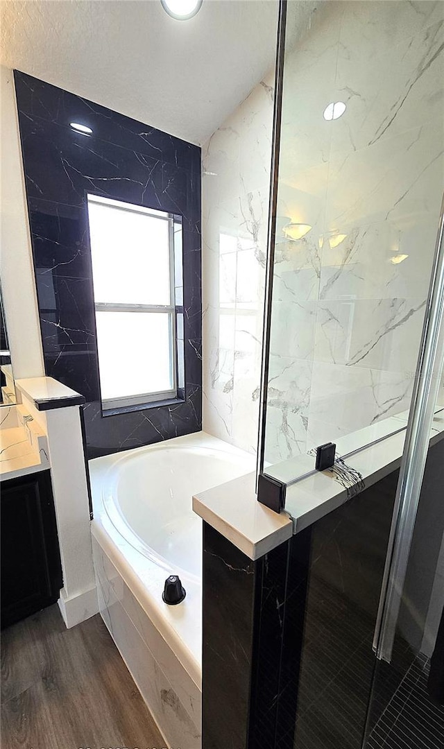 bathroom featuring vanity, hardwood / wood-style floors, and tiled tub