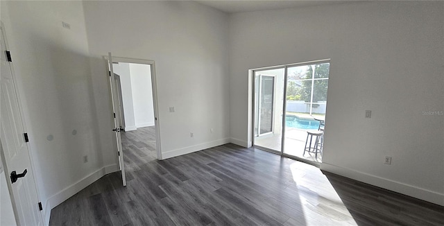 spare room featuring dark wood-type flooring and a high ceiling