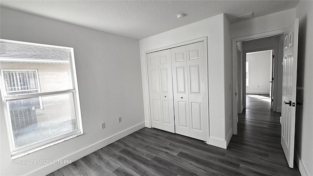 unfurnished bedroom with dark wood-type flooring, a closet, and a textured ceiling