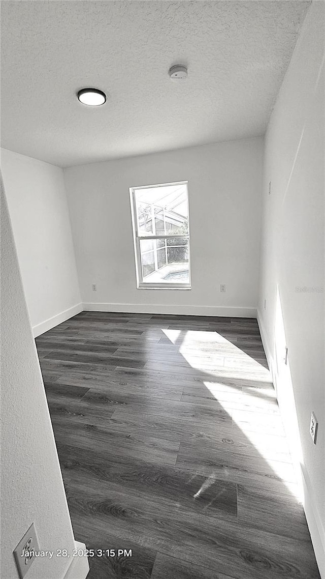 empty room featuring dark hardwood / wood-style floors and a textured ceiling