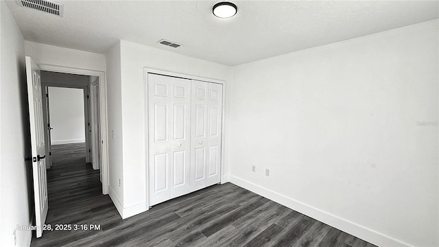 unfurnished bedroom featuring dark wood-type flooring, a textured ceiling, and a closet