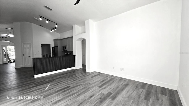 unfurnished living room featuring track lighting, high vaulted ceiling, dark hardwood / wood-style floors, and a textured ceiling