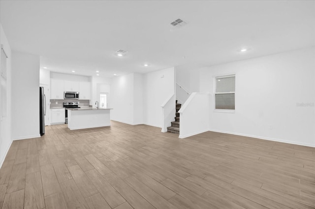 unfurnished living room featuring sink and light wood-type flooring