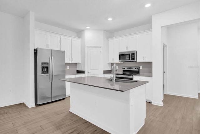 kitchen with white cabinetry, stainless steel appliances, and an island with sink