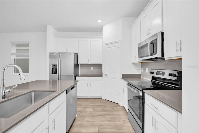 kitchen featuring appliances with stainless steel finishes, sink, decorative backsplash, and white cabinets