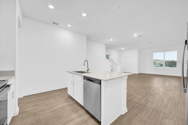 kitchen with appliances with stainless steel finishes, an island with sink, sink, white cabinets, and light hardwood / wood-style floors