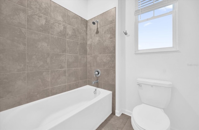 bathroom featuring tiled shower / bath, tile patterned floors, and toilet