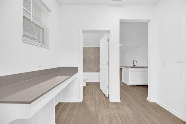 bathroom with wood-type flooring, sink, a washtub, and toilet