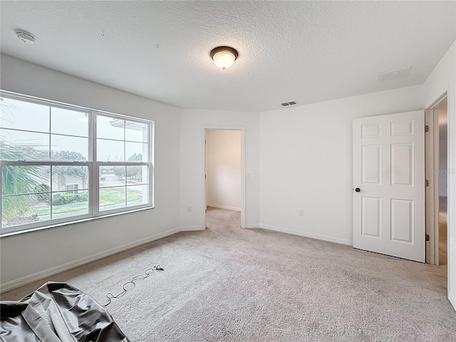 unfurnished room with light carpet and a textured ceiling