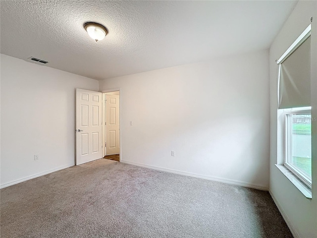 unfurnished room featuring carpet flooring and a textured ceiling