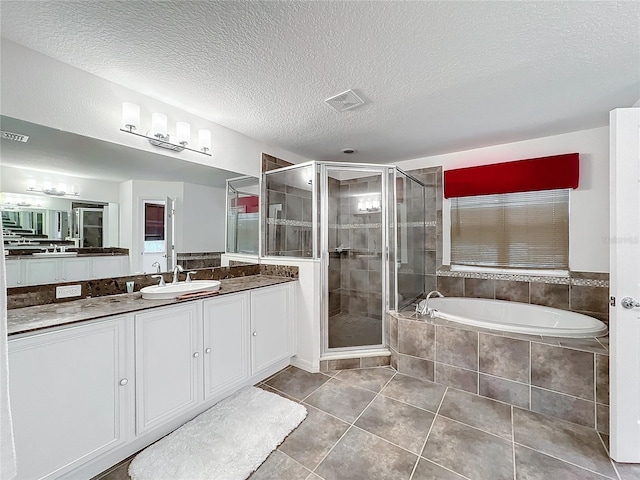 bathroom featuring shower with separate bathtub, tile patterned floors, vanity, and a textured ceiling