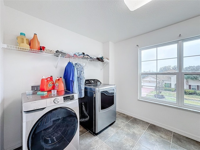 laundry area with washer and clothes dryer, tile patterned floors, and a textured ceiling