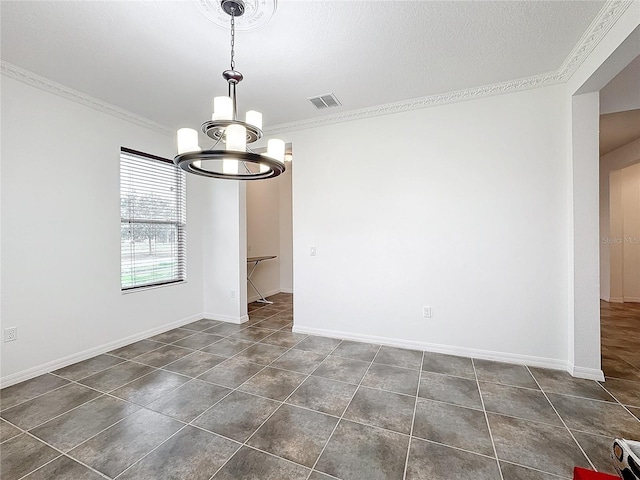 empty room with dark tile patterned flooring, a textured ceiling, ornamental molding, and a chandelier