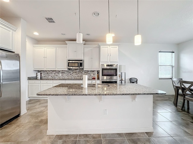 kitchen featuring pendant lighting, stainless steel appliances, and an island with sink