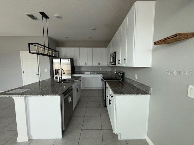 kitchen with dark stone countertops, black appliances, white cabinets, a kitchen island, and decorative light fixtures