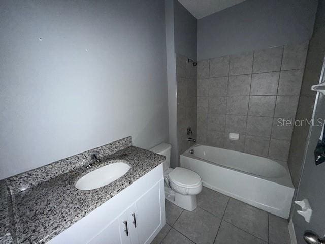 full bathroom featuring tile patterned flooring, vanity, tiled shower / bath, and toilet