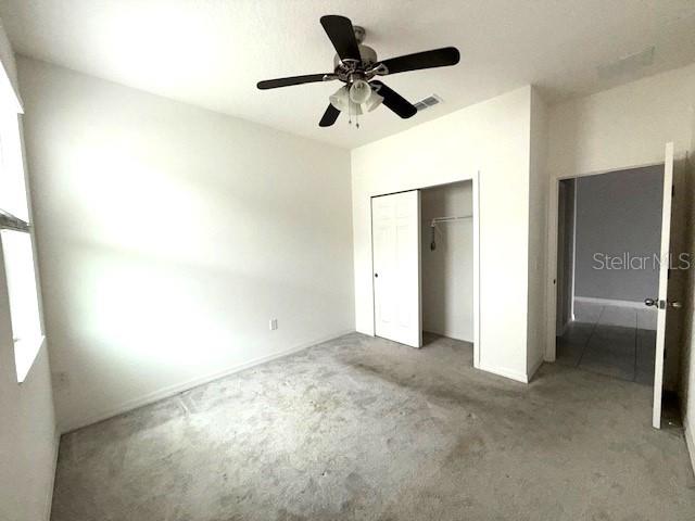 unfurnished bedroom with a closet, ceiling fan, and carpet