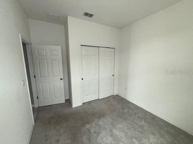 unfurnished bedroom featuring dark carpet and a closet