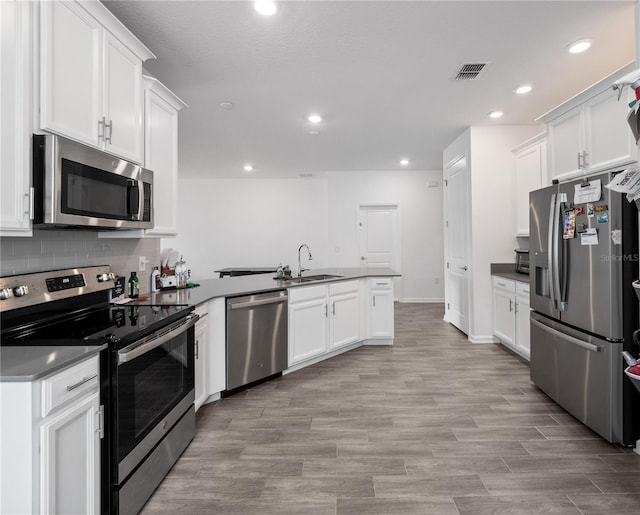 kitchen with sink, light hardwood / wood-style flooring, stainless steel appliances, white cabinets, and decorative backsplash