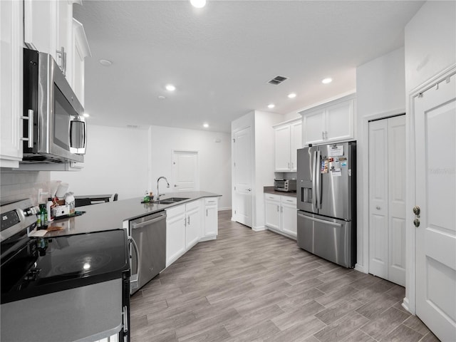 kitchen featuring stainless steel appliances, white cabinetry, and light hardwood / wood-style floors