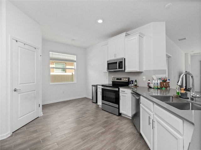 kitchen featuring sink, light hardwood / wood-style flooring, white cabinets, and appliances with stainless steel finishes