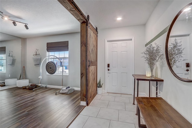 foyer featuring a barn door, a textured ceiling, and light hardwood / wood-style floors