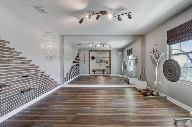 entrance foyer with track lighting, dark hardwood / wood-style flooring, and a textured ceiling